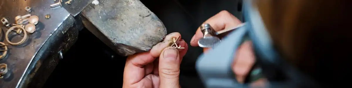 Atelier de bijuterii din București, bijutier lucrând manual la o piesă din aur cu instrumente fine și lumină caldă.