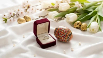 Cadouri de Paște bijuterii: inele cu diamant și ou încondeiat pe fundal de mătase la Bijuterii Persian.